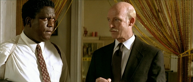 Medium shot frame from Léon — standing, room, suit