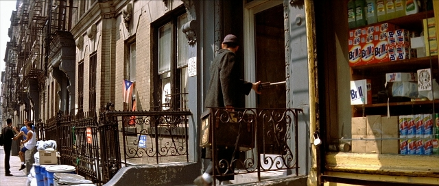 Wide shot frame from Léon — standing, street, hat