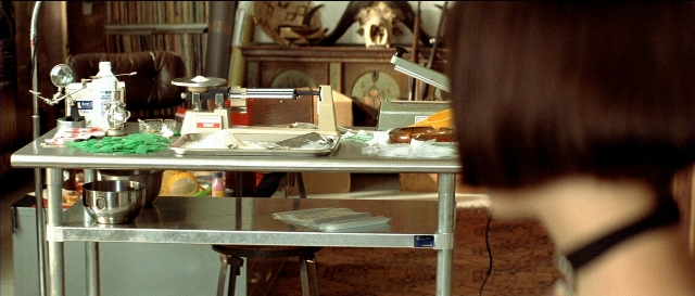 Wide shot frame from Léon — table, kitchen, water