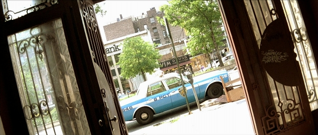 Wide shot frame from Léon — door, street, car