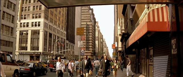 Wide shot frame from Léon — walking, street, car