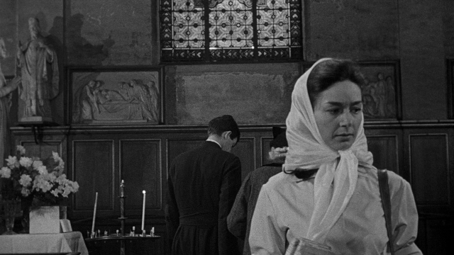 Wide shot frame from Léon Morin, prêtre — book, standing, table