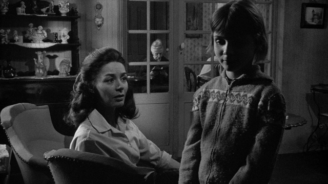 Wide shot frame from Léon Morin, prêtre — sitting, standing, room