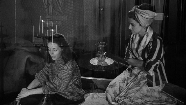 Wide shot frame from Léon Morin, prêtre — sitting, room, table