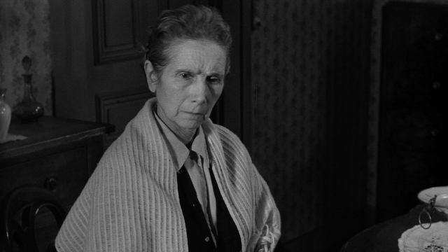 Wide shot frame from Léon Morin, prêtre — sitting, plate, room