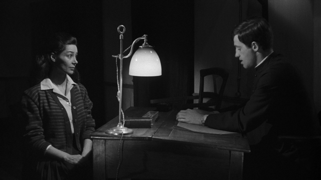 Wide shot frame from Léon Morin, prêtre — sitting, room, table