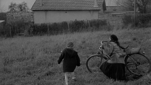 Wide shot frame from Léon Morin, prêtre — sitting, walking, dialogue