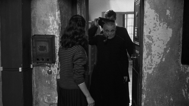 Wide shot frame from Léon Morin, prêtre — standing, walking, room