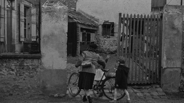 Wide shot frame from Léon Morin, prêtre — walking, street, house