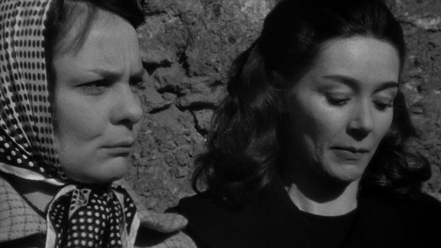 Close-up frame from Léon Morin, prêtre — standing, face, hair
