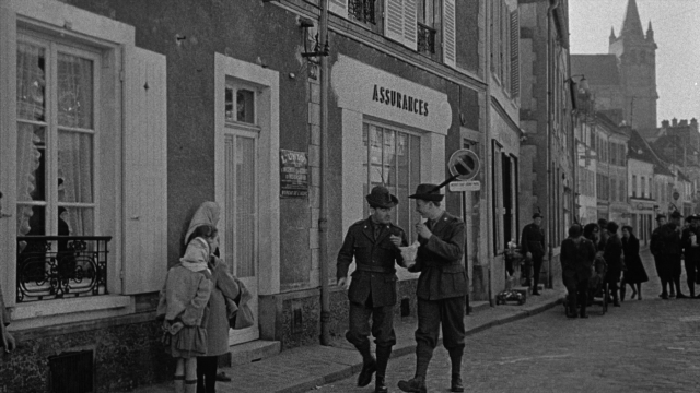 Wide shot frame from Léon Morin, prêtre — walking, dialogue, street