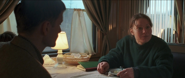 Wide shot frame from Compartiment n°6 — sitting, book, room