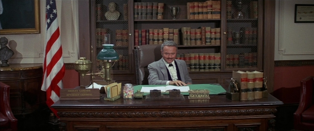 Wide shot frame from Blazing Saddles — sitting, desk, book