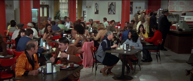 Wide shot frame from Blazing Saddles — sitting, standing, table
