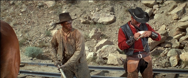 Wide shot frame from Blazing Saddles — standing, plate, hat