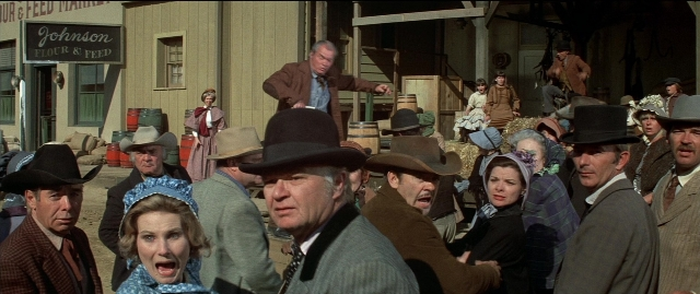 Wide shot frame from Blazing Saddles — standing, dialogue, door
