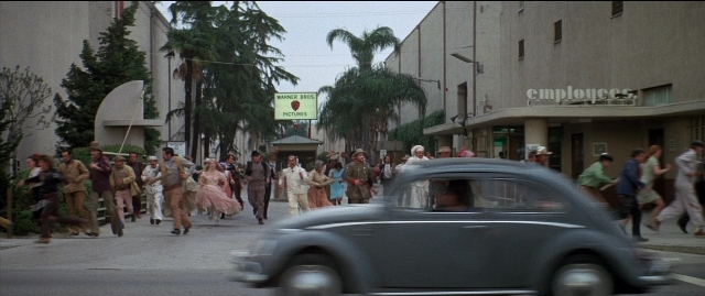 Wide shot frame from Blazing Saddles — walking, street, car