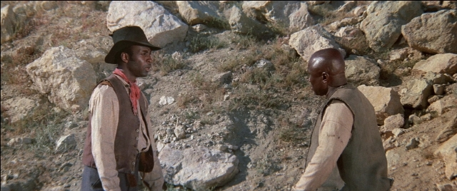 Wide shot frame from Blazing Saddles — standing, dialogue, hat