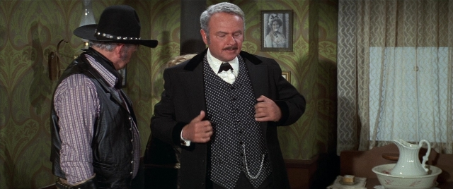 Wide shot frame from Blazing Saddles — standing, room, table