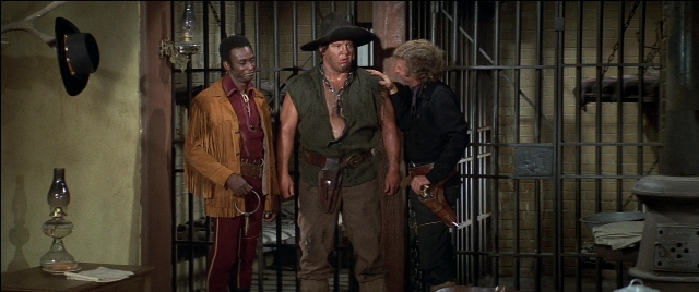 Wide shot frame from Blazing Saddles — standing, room, hat