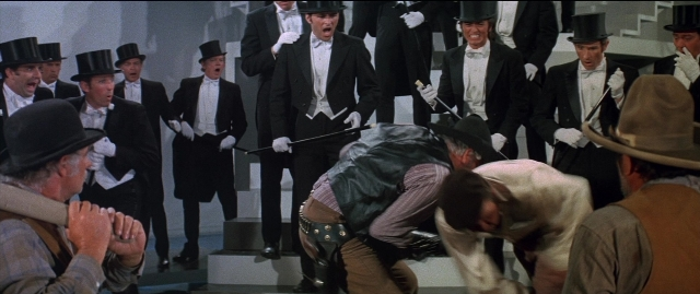 Wide shot frame from Blazing Saddles — standing, dialogue, hat