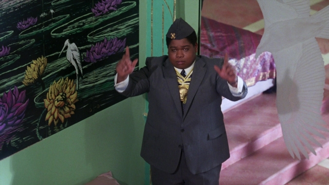 Wide shot frame from Coming to America — standing, room, hat