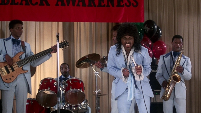 Wide shot frame from Coming to America — hair, guitar, saxophone