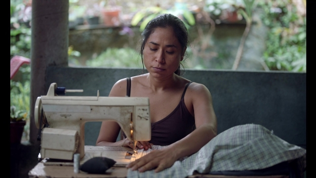Wide shot frame from Noche de Fuego — sitting, table, person
