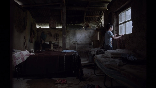 Frame from Noche de Fuego — standing, room, bed