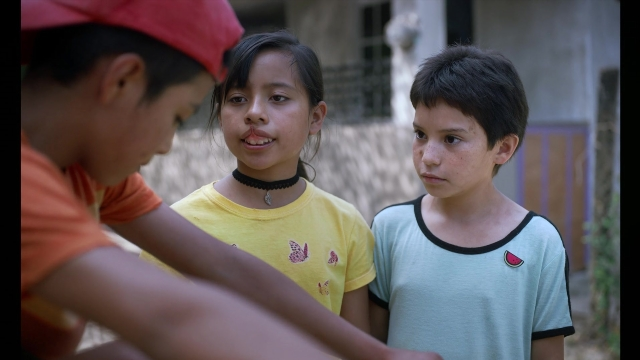 Medium shot frame from Noche de Fuego — standing, dialogue, hat