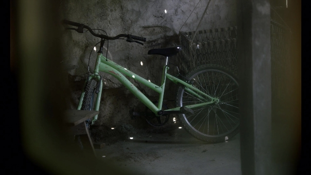 Wide shot frame from Noche de Fuego — room, bicycle, bicycle wheel
