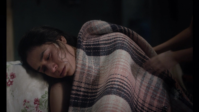 Frame from Noche de Fuego — bed, hand, person