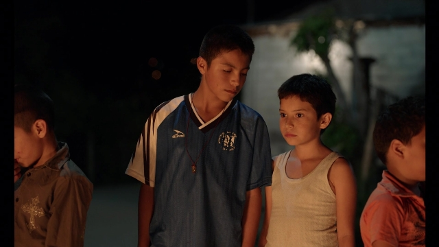 Wide shot frame from Noche de Fuego — standing, shirt, person