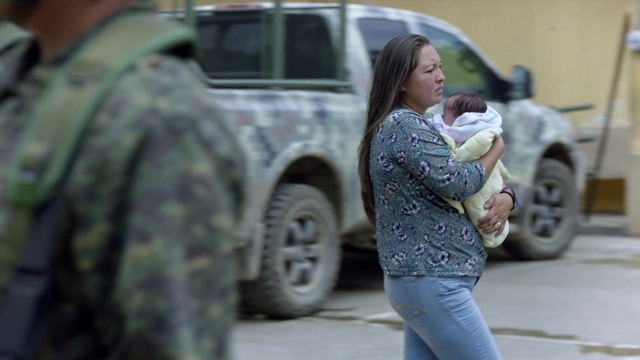Wide shot frame from Noche de Fuego — street, uniform, face