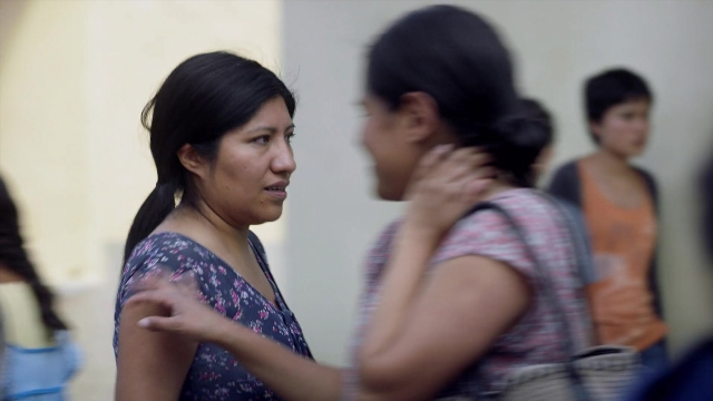 Wide shot frame from Noche de Fuego — standing, dress, face