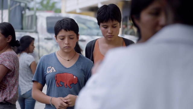 Wide shot frame from Noche de Fuego — standing, street, hand