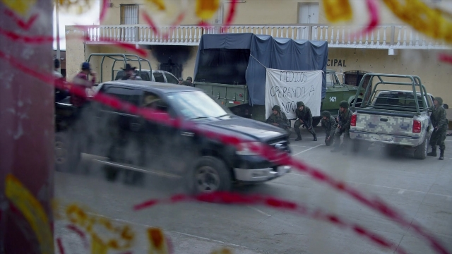 Wide shot frame from Noche de Fuego — standing, walking, street