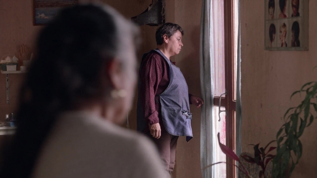 Wide shot frame from Noche de Fuego — standing, room, face