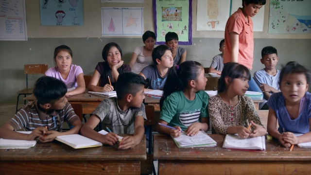 Wide shot frame from Noche de Fuego — sitting, standing, table