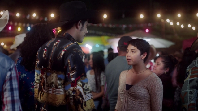 Wide shot frame from Noche de Fuego — standing, dialogue, hat