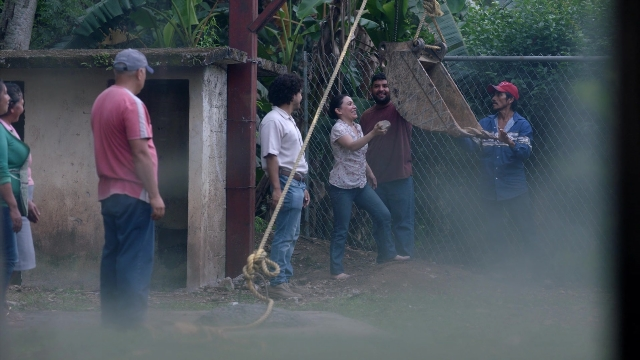 Wide shot frame from Noche de Fuego — standing, dialogue, hat