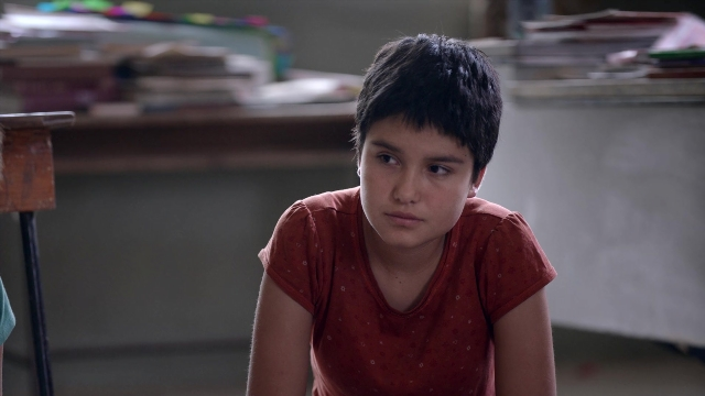 Medium shot frame from Noche de Fuego — sitting, shirt, face