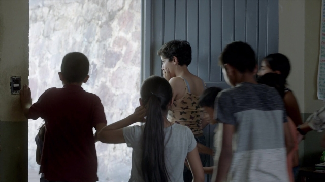 Wide shot frame from Noche de Fuego — standing, room, dialogue