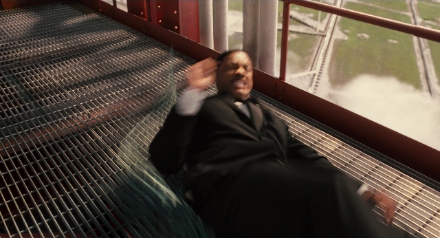 Wide shot frame from Men in Black 3 — sitting, street, suit