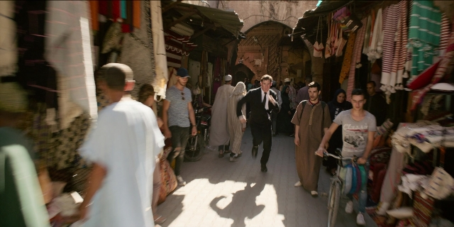 Wide shot frame from Men in Black International — walking, street, suit