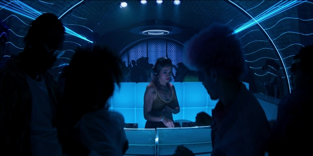 Wide shot frame from Men in Black International — sitting, standing, room