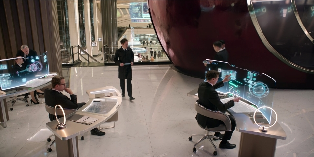 Wide shot frame from Men in Black International — sitting, room, table