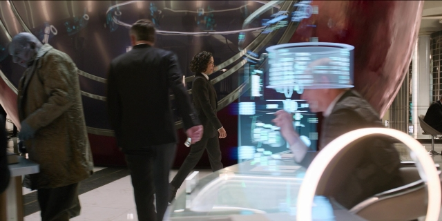 Frame from Men in Black International — sitting, walking, room