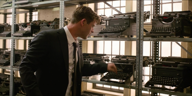Wide shot frame from Men in Black International — standing, room, suit