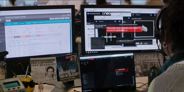 Wide shot frame from Men in Black International — office, face, laptop